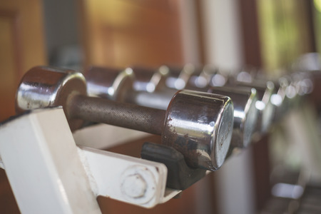 Gym equipment background with close up selective focus to a dumbbell