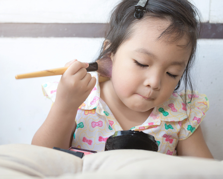 Closeup portrait of a little girl using face powder.の写真素材