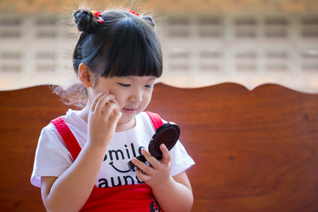 Closeup portrait of a little girl using face powderの写真素材