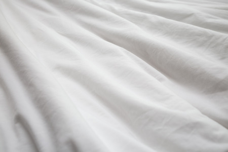 Creased white cloth material fragment as a background.の写真素材