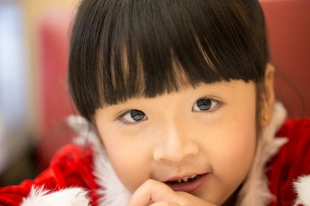 Close up happy little girl in santa claus costume over christmas.の写真素材