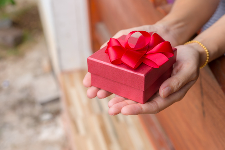 Woman holding a little gift box in a gesture of givingの写真素材