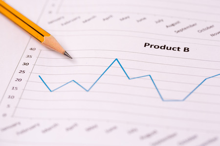Financial accounting and marketing graphs analysis with a pencil.