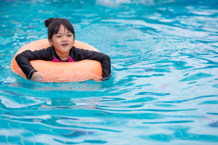 Asian girl with rubber ring in swimming pool.の写真素材