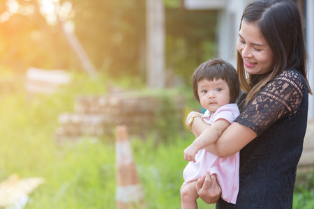 Asian woman carry her baby for love with on green nature background with copy space.の写真素材