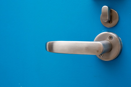 Close up of modern door handle on blue wooden door.の写真素材
