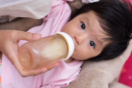 Mother feeding newborn son with feeding bottle.の写真素材
