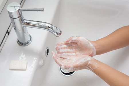 Kid washing hands in a white basin with a bar of white soap
