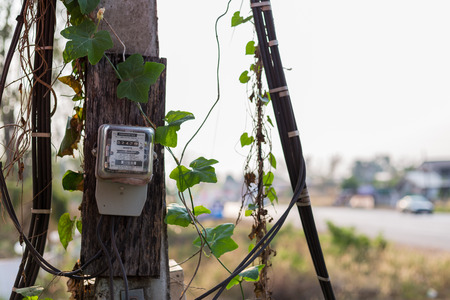 March 7th 2018 Udon Thani Thailand: Old electricity meter on electricity post in outdoor with vine...