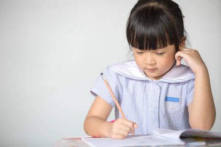 Little asian kid doing homework at home.