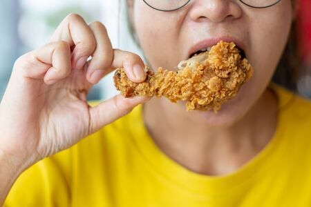 Young woman holding and eating fries chicken.の写真素材