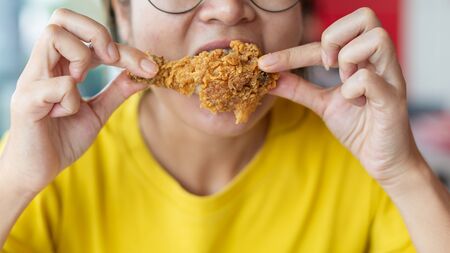 Young woman holding and eating fries chicken.の写真素材