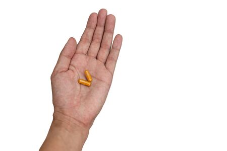 Hand of the patient holding a yellow orange capsuleの写真素材