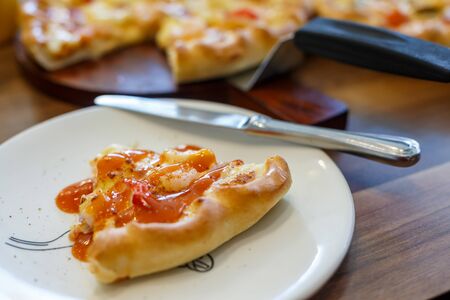 Seafood Italian Pizza slice on wood dish.