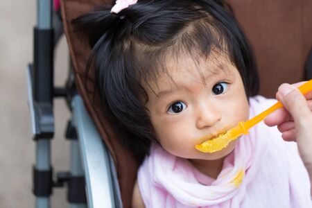 Close up infant baby feeding food on the kid chairの写真素材