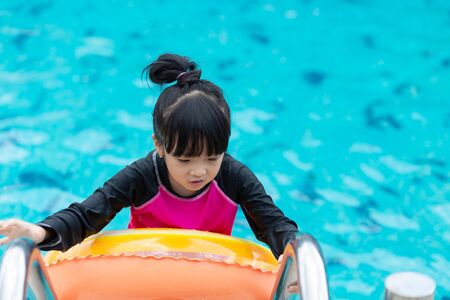 Asian girl with rubber ring in swimming pool.の写真素材
