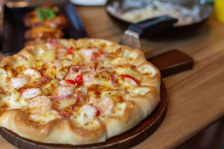 Seafood Italian Pizza slice on wood dish.の写真素材