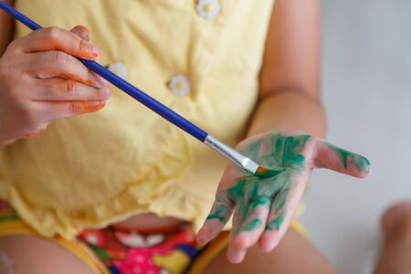 Kid paint her hands with brushesの写真素材