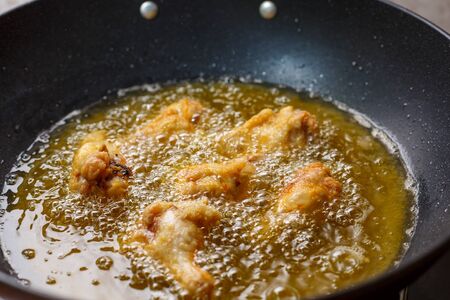 Close up fried chicken wings in boiling oil.