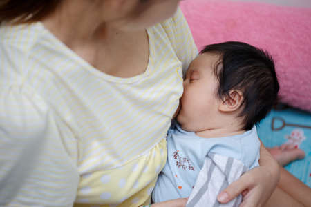 young mother breastfeeding newborn baby at home.