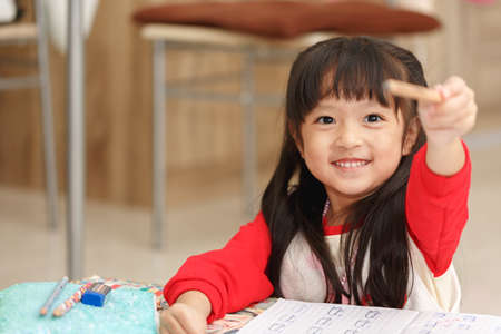 Asian little girl learning and writing in notebook with pencil.の写真素材
