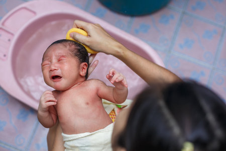Asian new born having a bath by mother.
