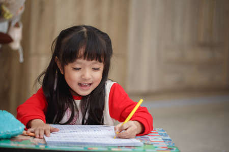 Asian little girl learning and writing in notebook with pencil.の写真素材