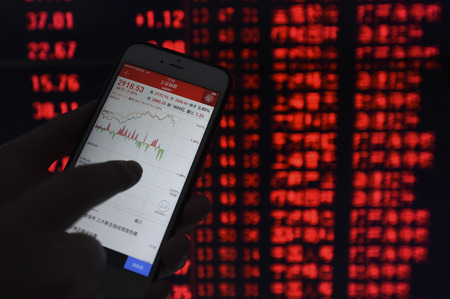 An investor checks stock market using a smartphone at a securities firm in Shenyang, capital of northeast China's Liaoning Province. China's stocks closed higher on Monday, with the benchmark Shanghai Composite Index up 2.35 percent, to close at 2,927.18 のeditorial素材