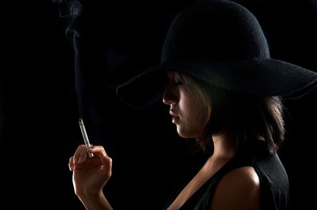 Pretty girl smokes a cigarette in the darkの写真素材