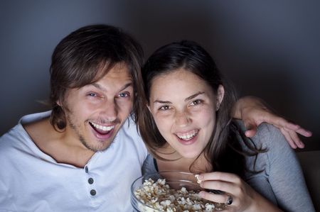 Young couple at home watching a movie with popcornの写真素材