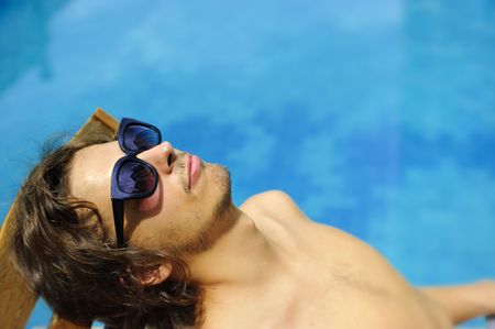 Man tanning poolside on a summer dayの写真素材