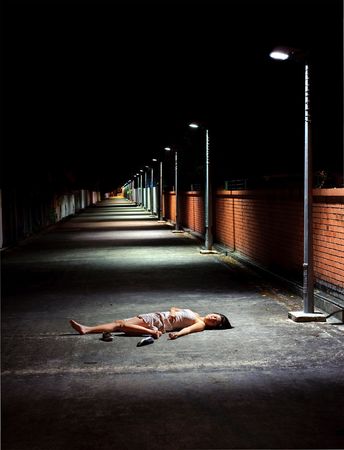 Dark and dangerous, girl sleeps in streetの写真素材