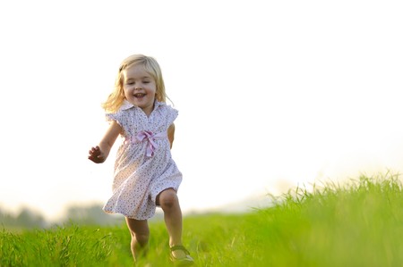 Young girl runs through a field, happy and having fun.の写真素材