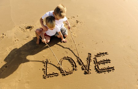 Lovely young brother and sister write words in the sand togetherの写真素材