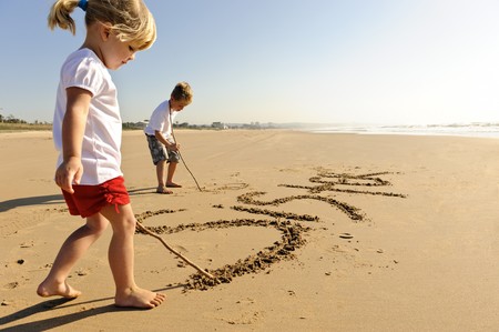 Lovely young brother and sister write words in the sand togetherの写真素材