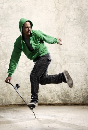Skilled skateboarder does a trick in front of grunge wallの写真素材