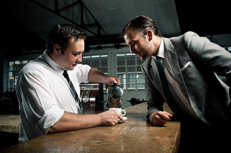 Man in suit looks at how the barista pours the next cup of coffeeの写真素材