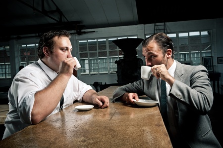two men share some coffee and look at each other while drinkingの写真素材