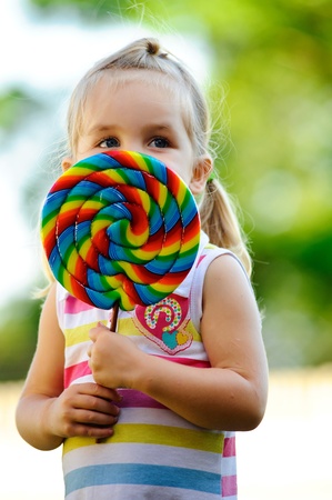 Young girl holds her big colourful lollipopの写真素材