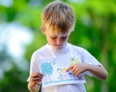 Cute child holds up drawing of a family の写真素材