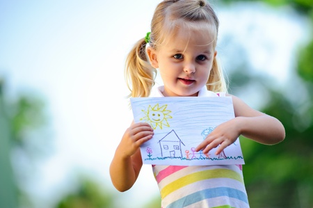 Cute child holds up drawing of a family の写真素材