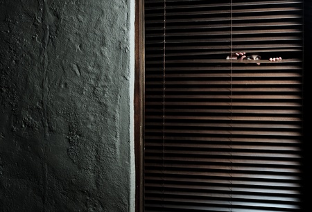 Mysterious woman pulls the blinds apart to see the outside world の写真素材