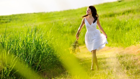 Candid skipping carefree adorable woman in field with flowers at summer sunset.の写真素材