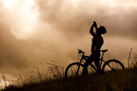 Attractive, healthy couple drink from their water bottles on mountain bikes. active outdoor lifestyle concept の写真素材