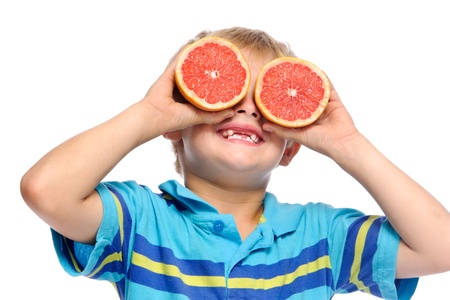 Blond boy covers eyes with ruby grapefruit; healthy living concept の写真素材