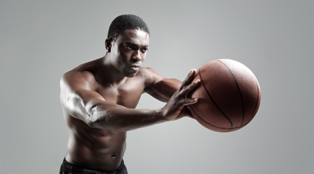 Shirtless muscular man passing a basketball in studio の写真素材