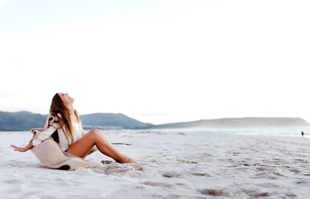 beach girl sits on the sand and opens her arms in a display of freedom and joy (panormaic large image with copyspace)の写真素材