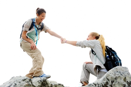 Hiking woman helps her friend climb onto the rock, outdoor lifestyle conceptの写真素材