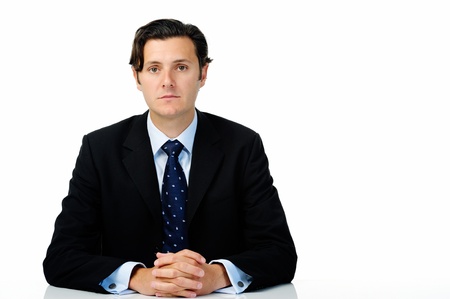 Successful businessman poses for a portrait while seated at a table, isolated on white