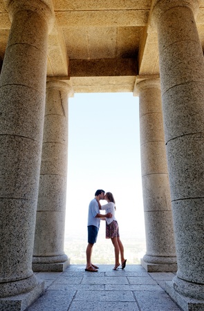 tourist couple kiss each other while visiting an old monument while traveling. a real young couple in loveの写真素材